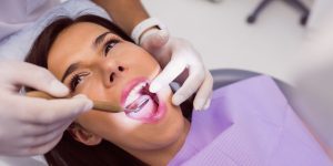 Close up of dentist examining female patient teeth with a mouth mirror